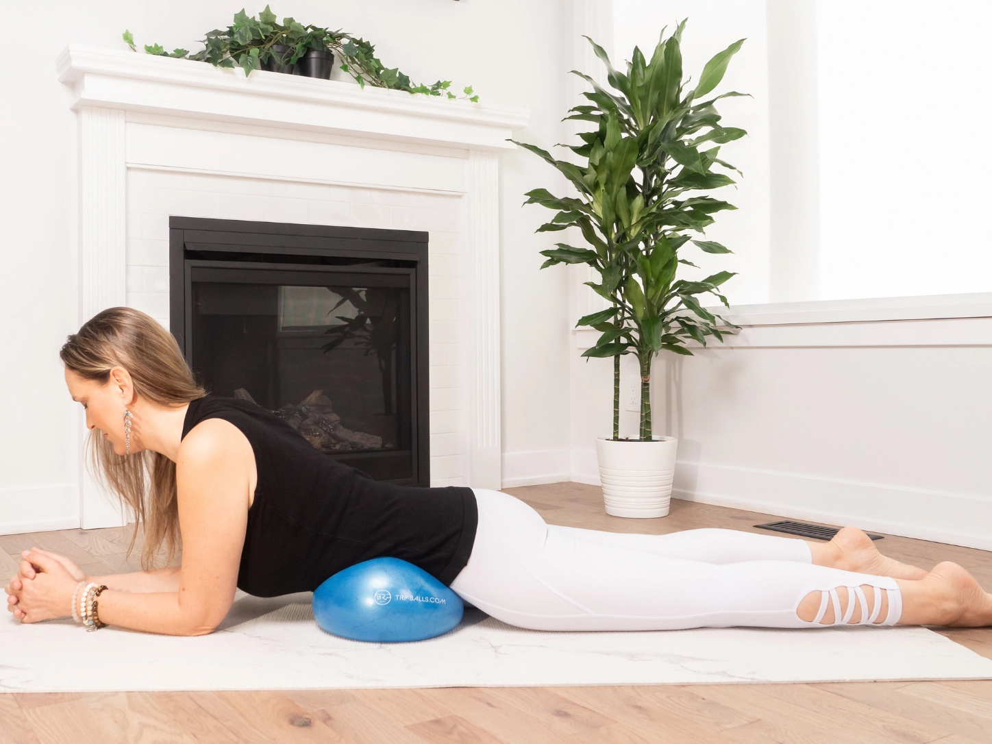 Femme réalisant un exercice de relâchement du bassin avec un ballon Mama placé sous les hanches, sur un tapis de yoga.
